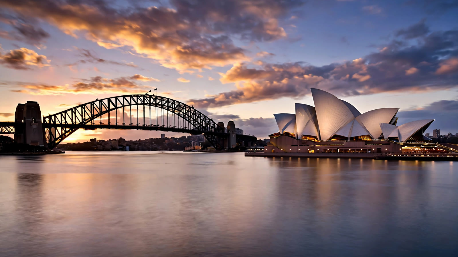 Sydney Harbour at dusk: the Bridge silhouetted against the sunset and the Opera House lit on the right