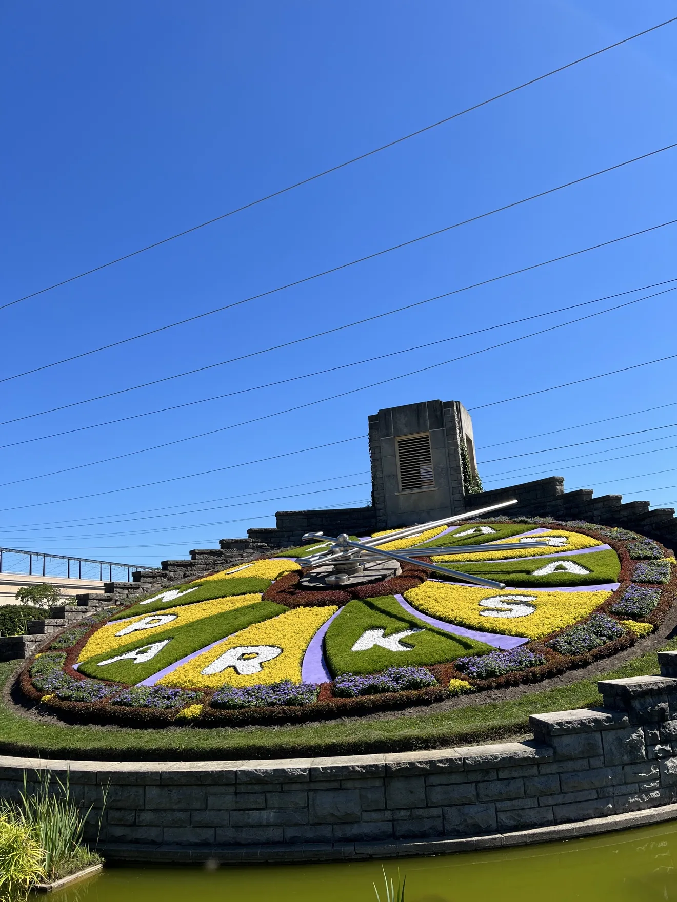 Close on the Floral Clock: petal numerals, metal hands and the stone tower above