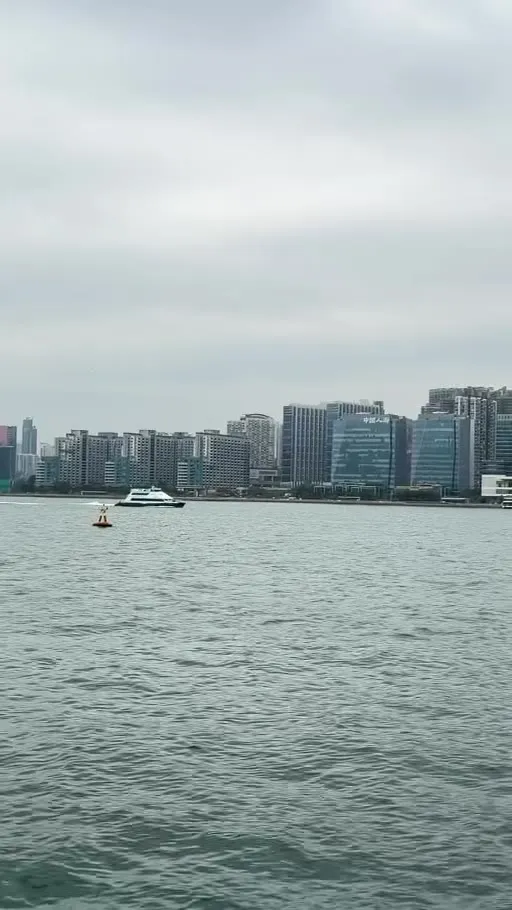 A ferry crossing Victoria Harbour with towers on the far shore
