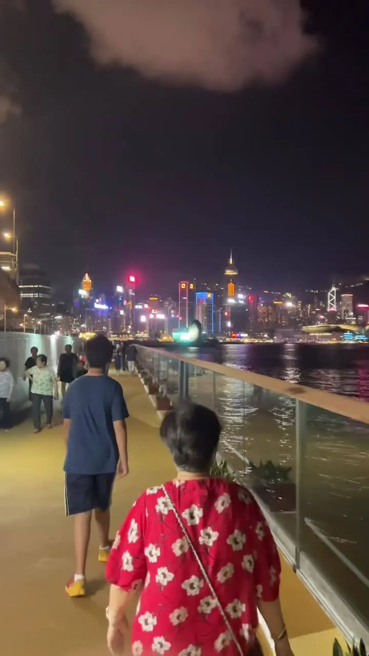 Family walking the waterfront at night with harbour lights across the water