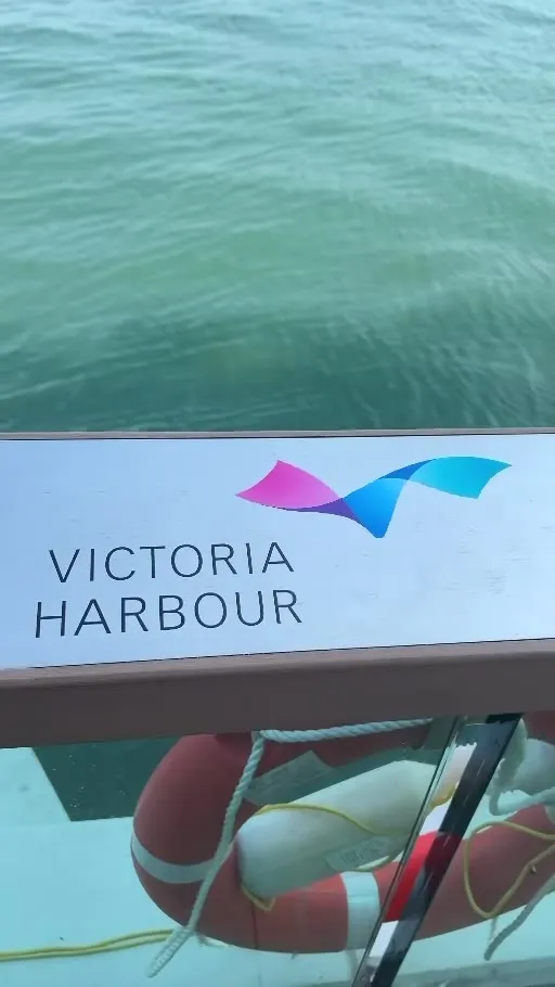 A VICTORIA HARBOUR sign on the waterfront railing