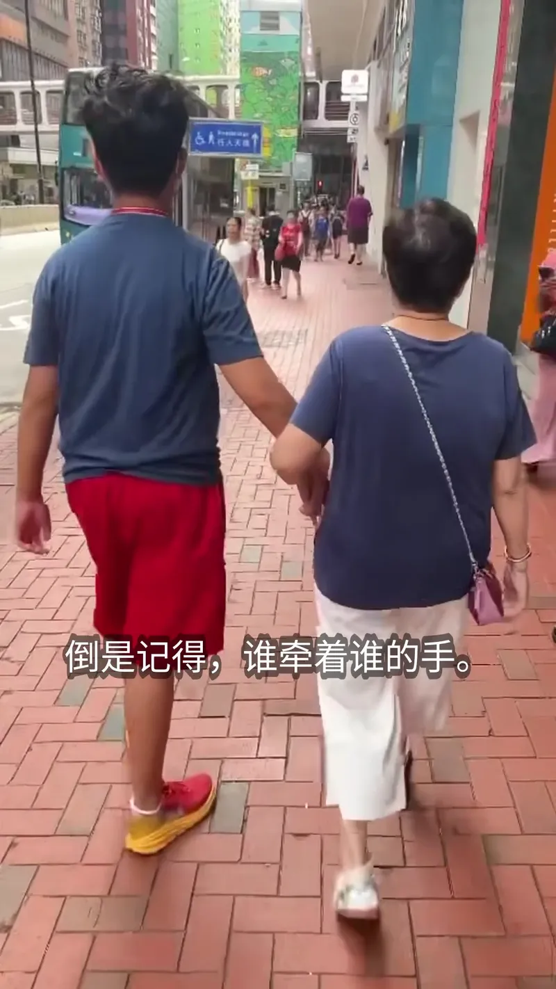 An older couple walking slowly on a pedestrian street, seen from behind
