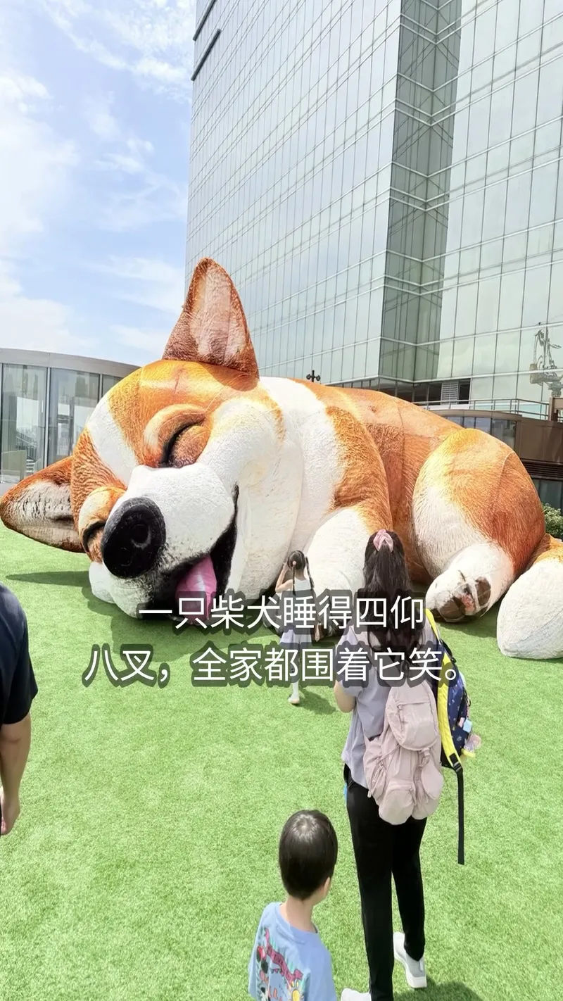 A giant sleeping Shiba sculpture with family around it