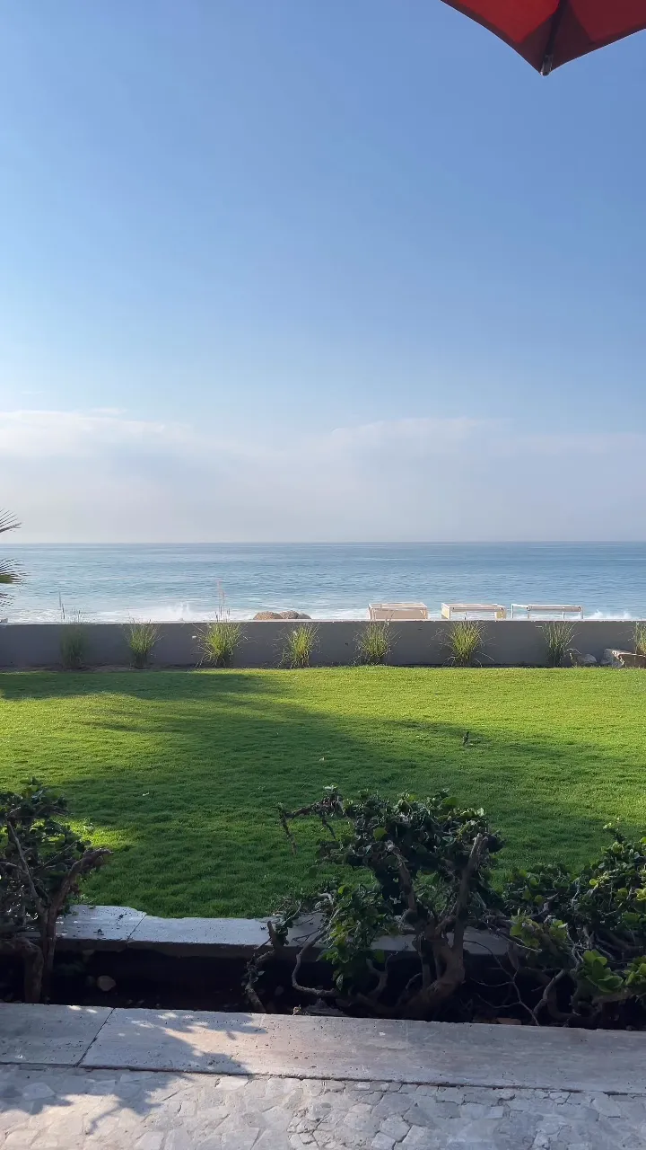Los Cabos 度假村露台上的一片綠草坪,一路延伸到矮牆邊,牆外是海和拍岸的浪