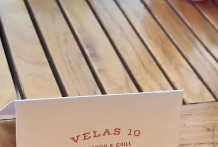 Tarjeta Velas 10 Seafood & Grill sobre mesa de madera