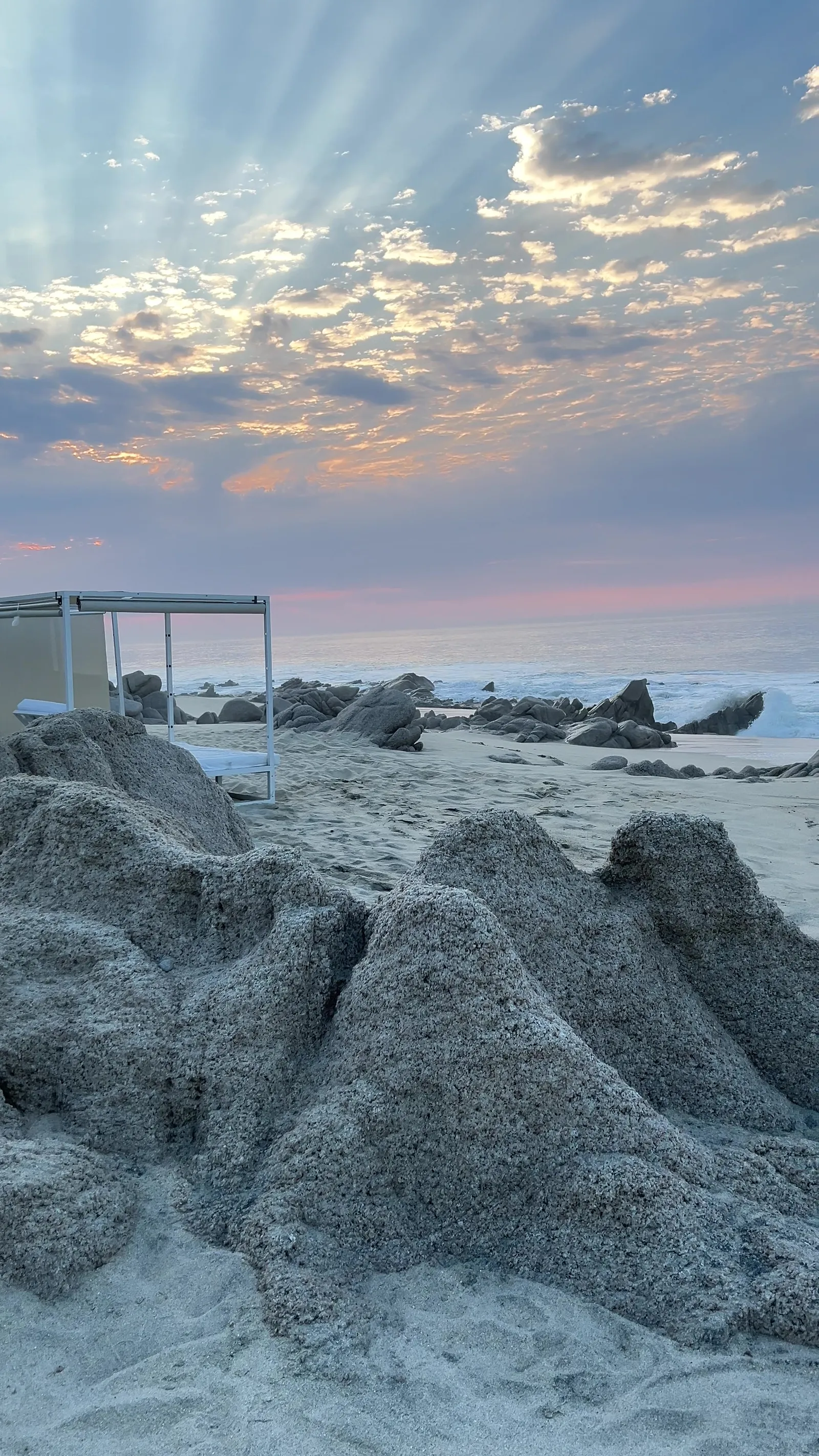 Rayos crepusculares sobre cabañas vacías y rocas en Los Cabos