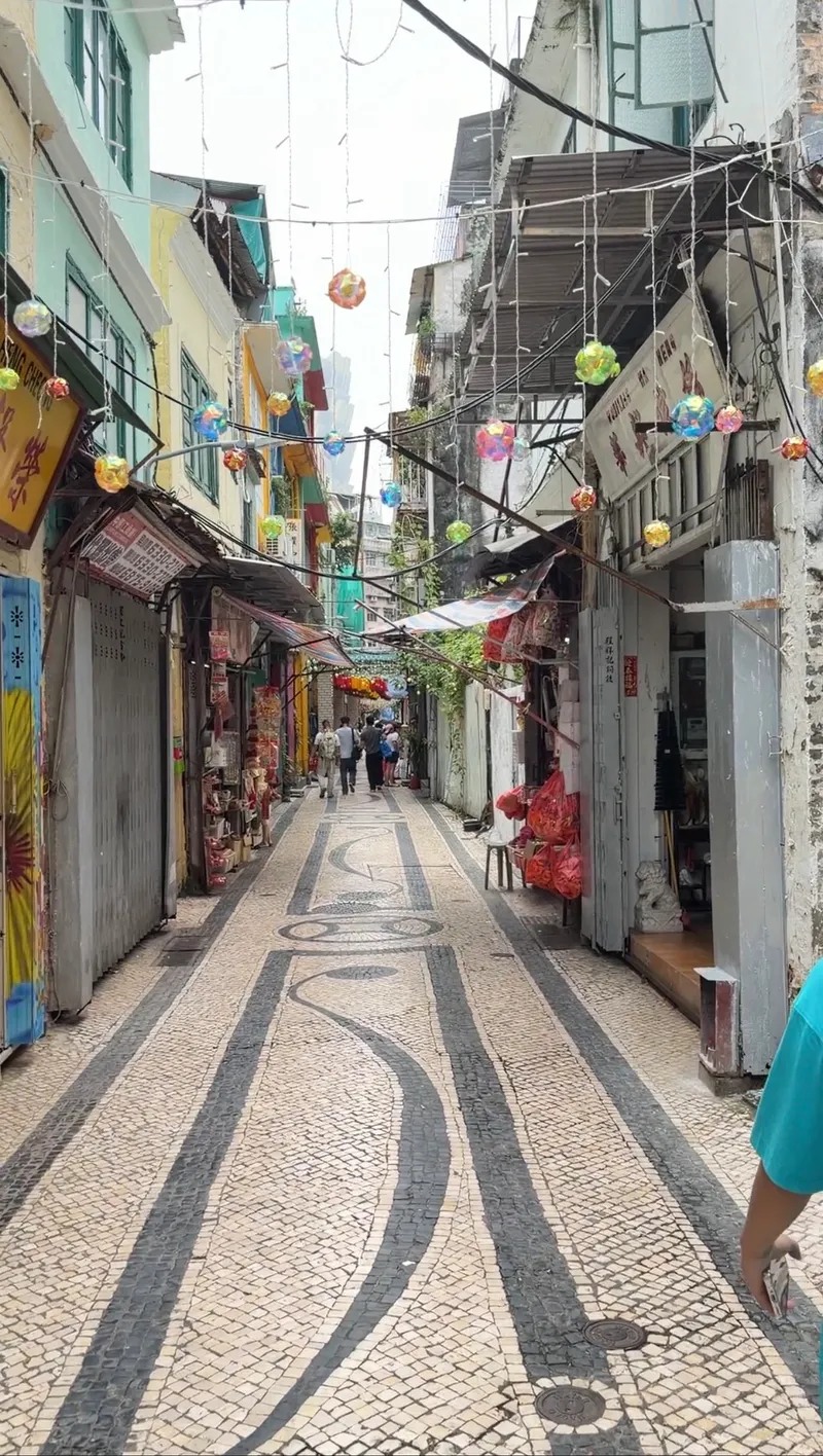 Portuguese wave-pattern paving and lanterns in a Macau old-town alley