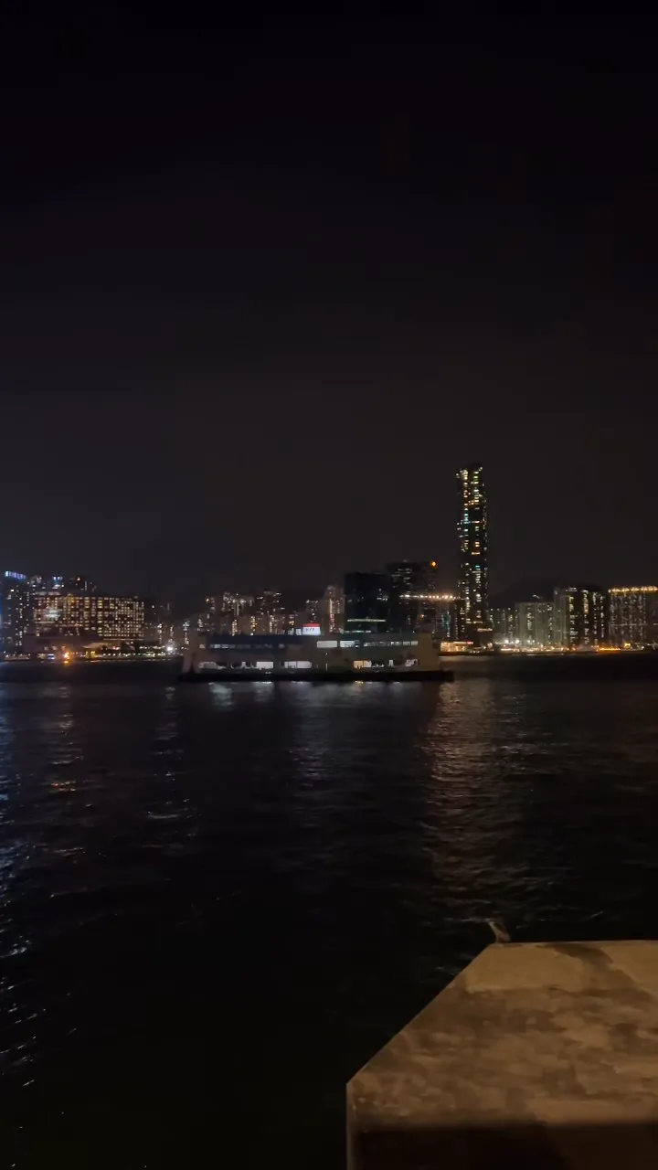 Victoria Harbour at night, a ferry crossing the dark water