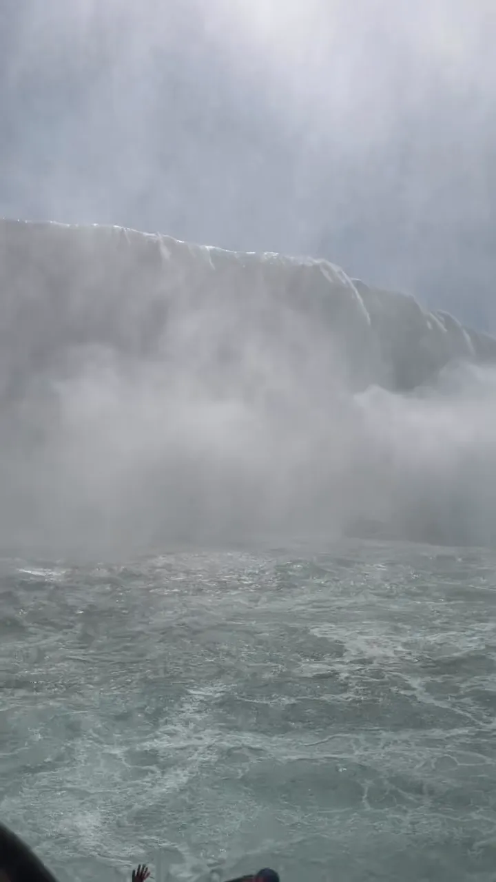 The Horseshoe Falls as a grey-green wall of water and mist, seen from the boat's bow
