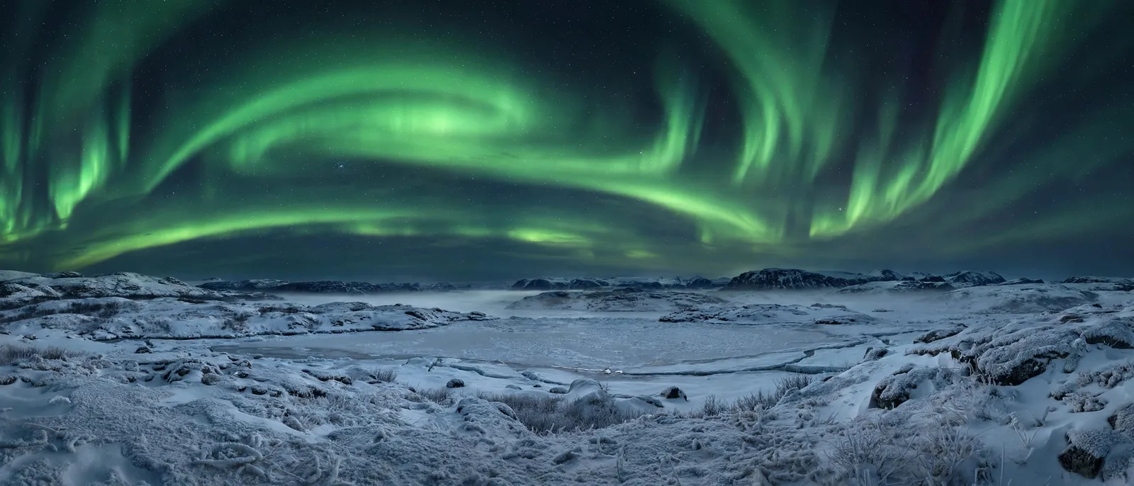 Auroras boreales en cintas verdes sobre un paisaje ártico nevado
