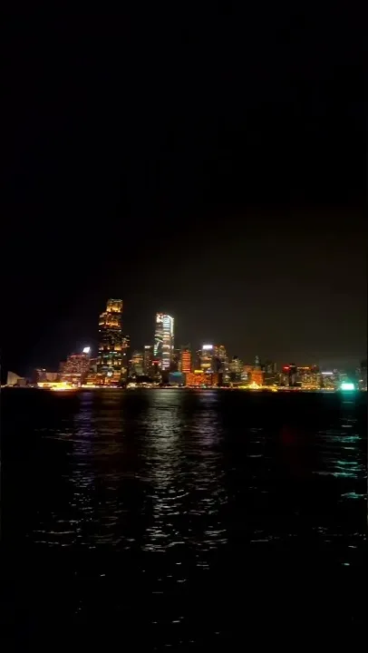 Torres brillando al otro lado del puerto Victoria de noche, vistas desde el paseo a oscuras